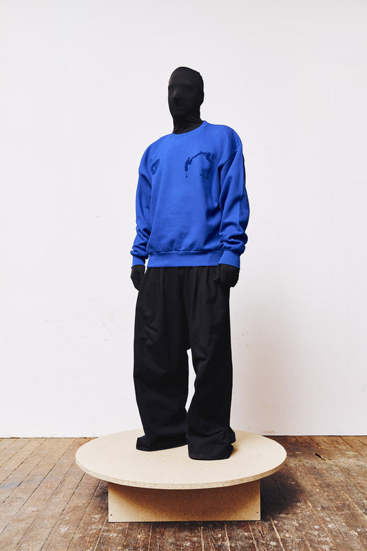 Man wearing blue sweatshirt by A BIT FRESH AIR with blue flock transfer print on the chest – modern streetwear look.